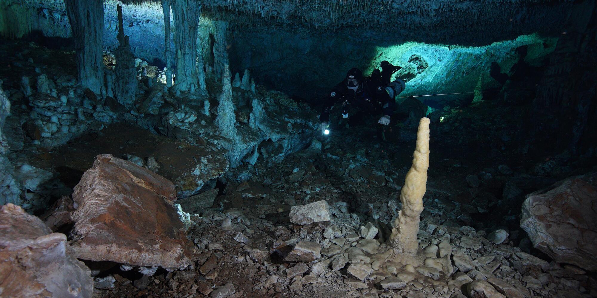 Image of underwater cave beneath the Yucutan Peninsula. A diver with a flashlight is seen in the cave.